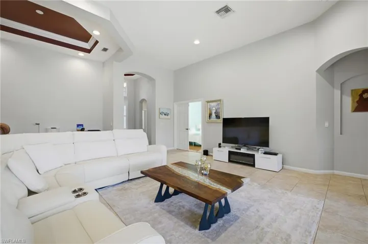 Living room featuring arched walkways, light tile patterned flooring, and recessed lighting