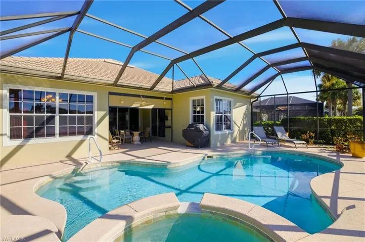 View of pool featuring a sunroom, a lanai, a patio, a pool with connected hot tub, and a grill