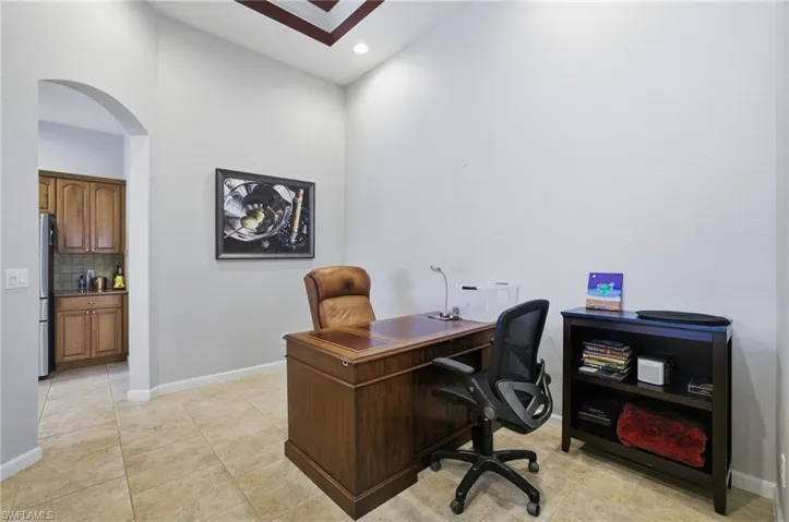 Office space with arched walkways, recessed lighting, and light tile patterned floors