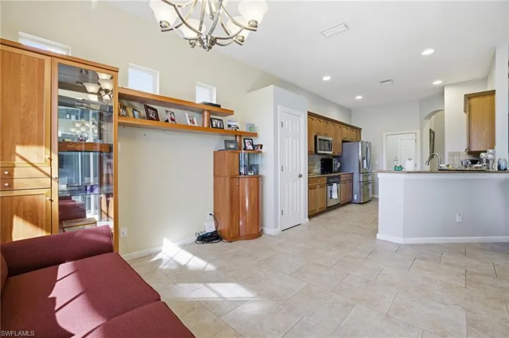 Kitchen featuring arched walkways, brown cabinets, a chandelier, appliances with stainless steel finishes, and backsplash