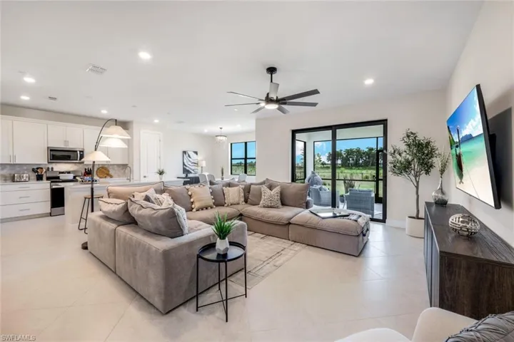 Living room featuring ceiling fan, light tile flooring, and sink