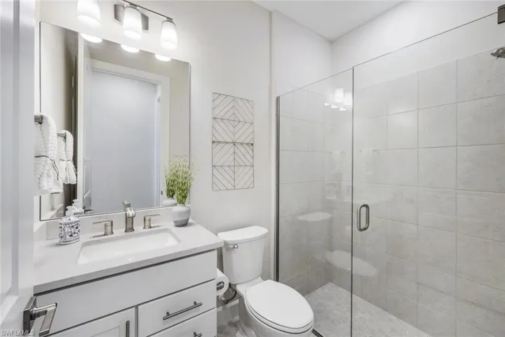 Bathroom featuring an enclosed shower, toilet, and vanity