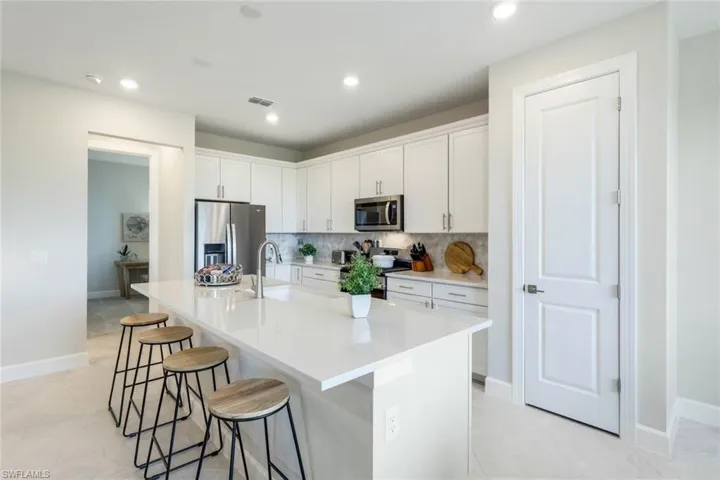 Kitchen with tasteful backsplash, a kitchen island with sink, appliances with stainless steel finishes, sink, and a breakfast bar