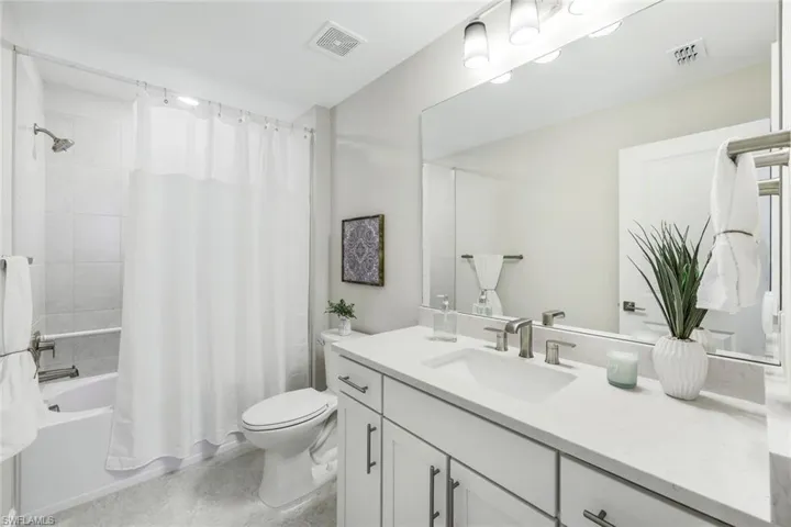 Full bathroom with tile flooring, shower / bath combination with curtain, toilet, and vanity