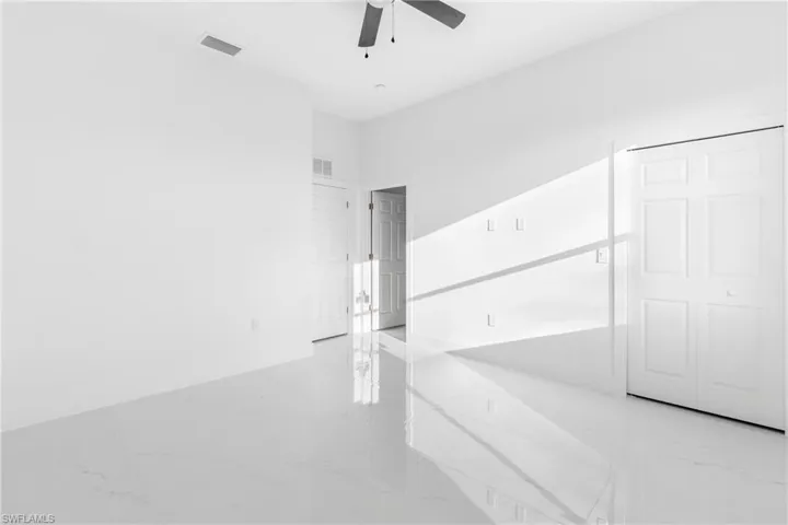 Empty room featuring ceiling fan, marble tiled floors, and baseboards