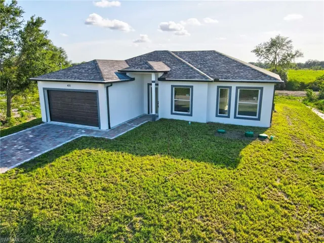 View of front of home featuring an attached garage, stucco siding, a shingled roof, and driveway