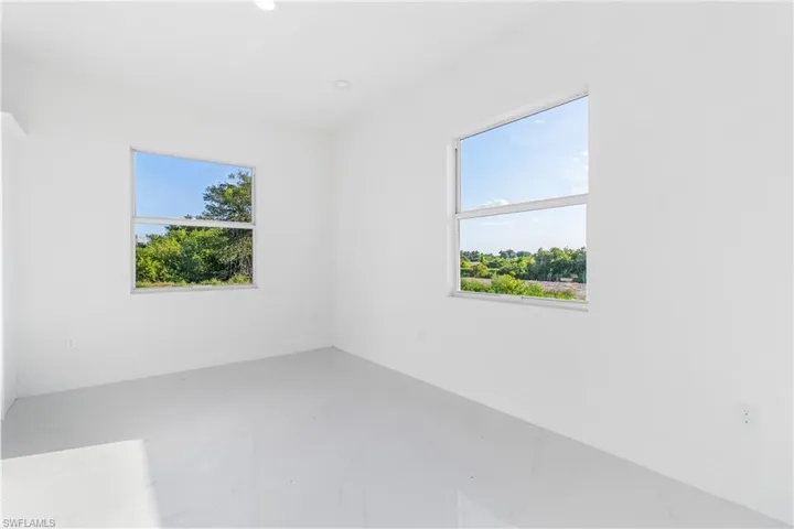 Empty room with plenty of natural light, marble tiled floors, baseboards, and recessed lighting