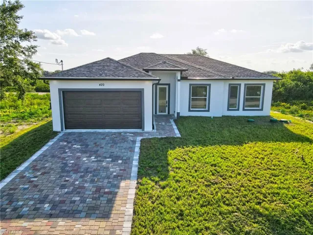 Ranch-style home with stucco siding, an attached garage, driveway, and a front lawn