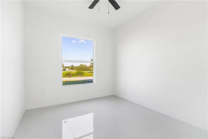 Spare room featuring light marble finish floors, ceiling fan, and baseboards