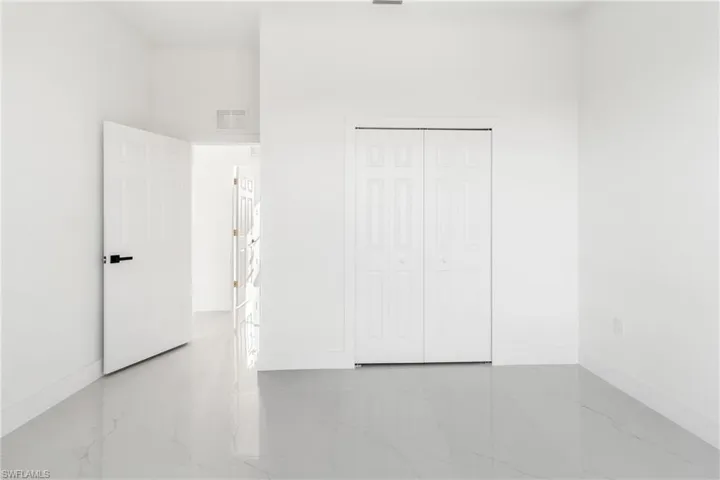 Unfurnished bedroom featuring marble tiled flooring, baseboards, and a closet