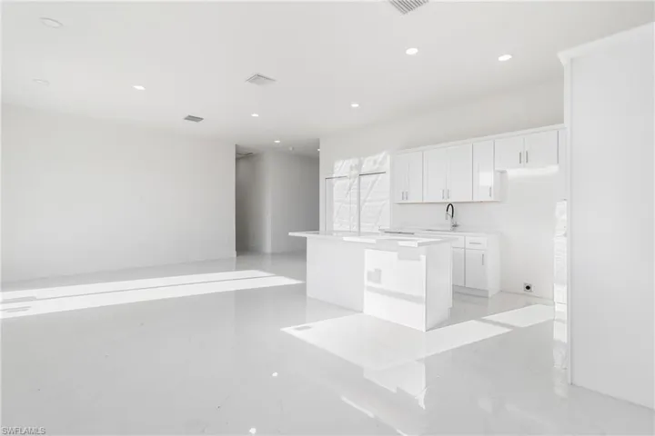 Kitchen with light marble finish flooring, white cabinetry, a kitchen island, recessed lighting, and light countertops