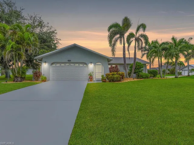 Ranch-style home with a garage and a yard