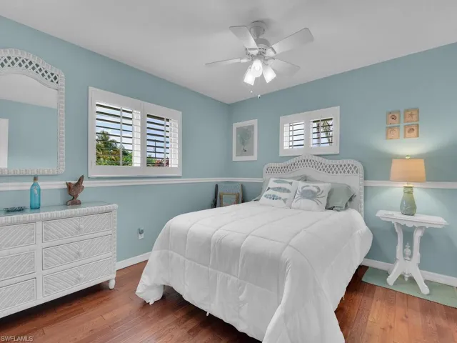 Bedroom with multiple windows, ceiling fan, and hardwood / wood-style floors