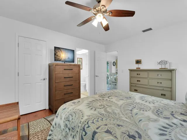 Bedroom with ensuite bath, ceiling fan, and hardwood / wood-style floors