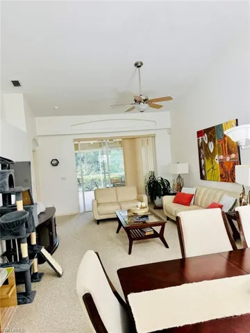Living area featuring light colored carpet, ceiling fan, and arched walkways