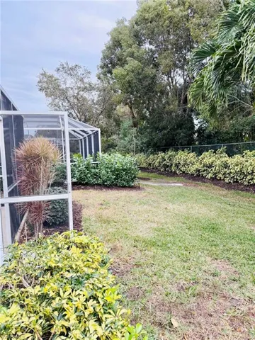 View of green lawn featuring a sunroom and a lanai