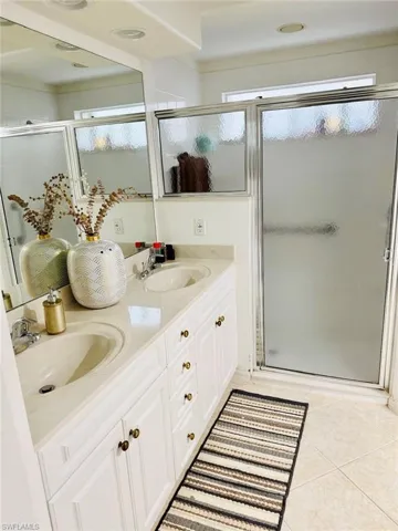 Full bath featuring double vanity, a shower stall, and light tile patterned floors
