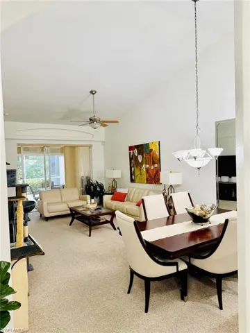 Living room with light carpet, a ceiling fan, and high vaulted ceiling