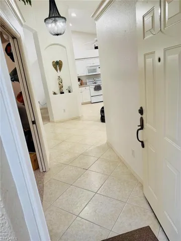 Hall with light tile patterned floors, a chandelier, and recessed lighting