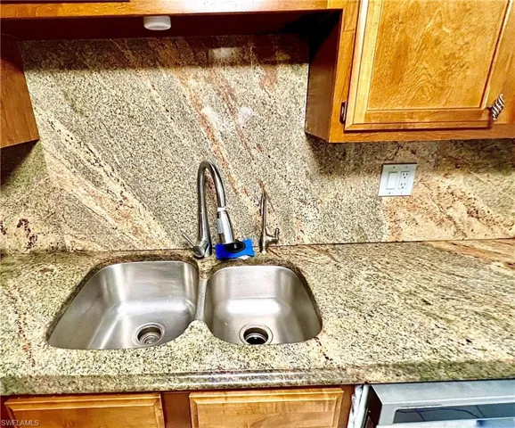 Details with sink, light stone countertops, and backsplash