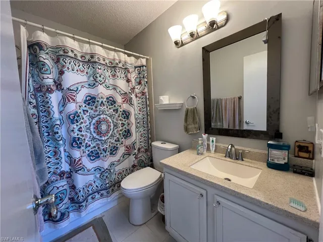 Bathroom featuring vanity, toilet, tile patterned floors, and a textured ceiling