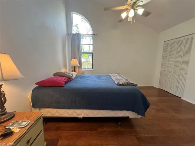 Bedroom with lofted ceiling, dark hardwood / wood flooring, a closet, and ceiling fan