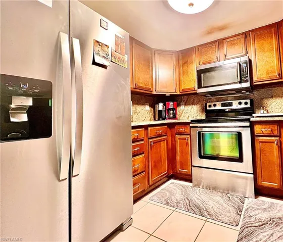 Kitchen featuring light tile patterned floors, decorative backsplash, and stainless steel appliances