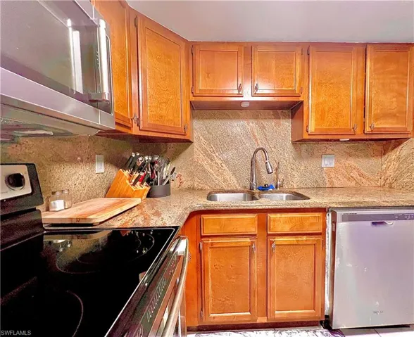 Kitchen with appliances with stainless steel finishes, decorative backsplash, and sink