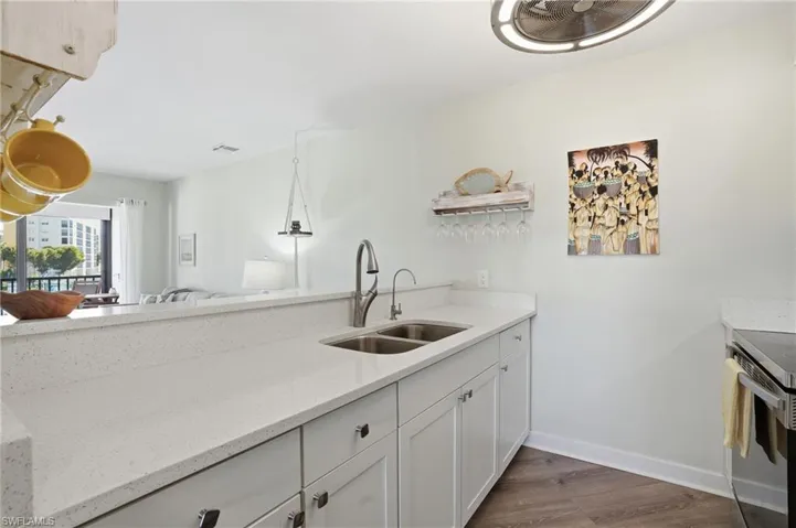 Kitchen featuring white cabinets, light stone counters, dark wood-type flooring, range with electric cooktop, and open floor plan