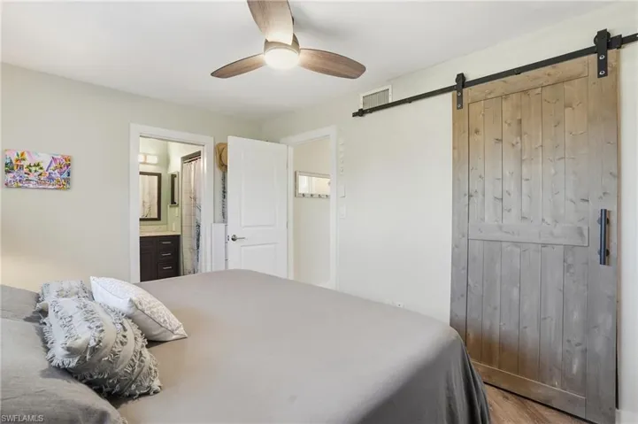 Bedroom with ceiling fan, wood finished floors, and ensuite bathroom