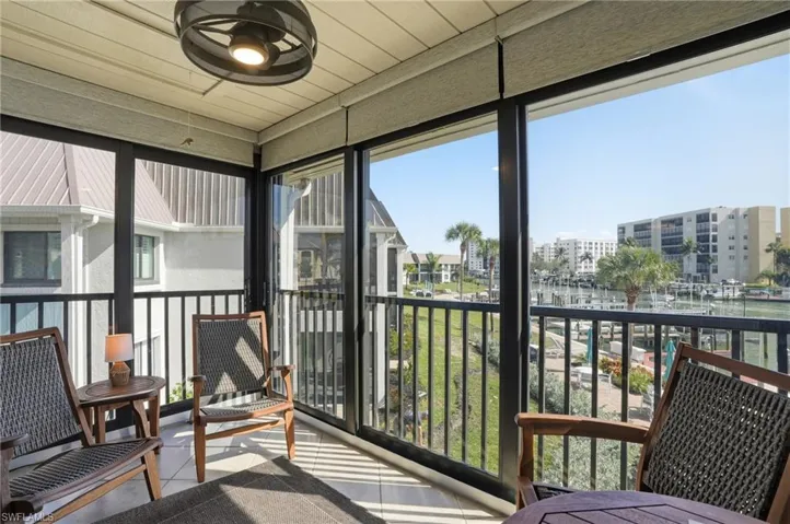 Sunroom with a water view, healthy amount of natural light, tile patterned floors, and a wall of windows