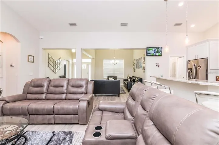 Living area with wood finished floors, a chandelier, recessed lighting, and arched walkways
