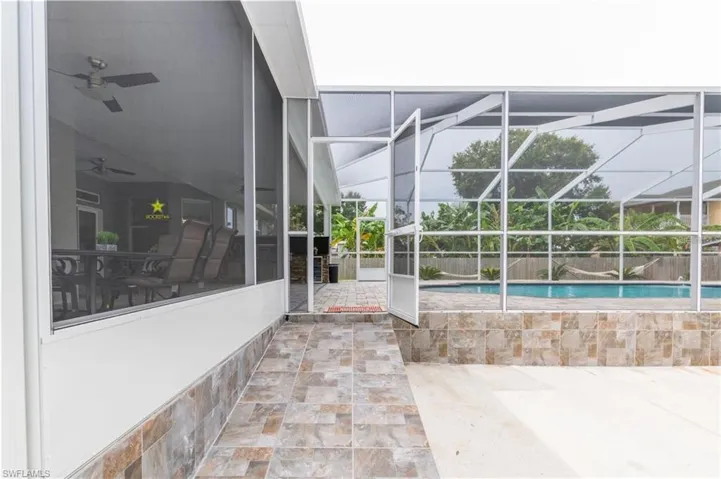 Swimming pool with glass enclosure, a patio area, and a sunroom