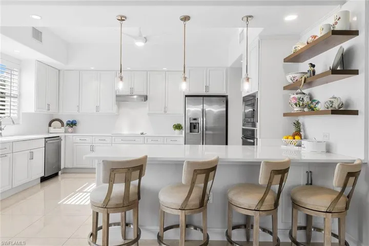 Kitchen featuring open shelves, a breakfast bar, hanging light fixtures, white cabinetry, and recessed lighting