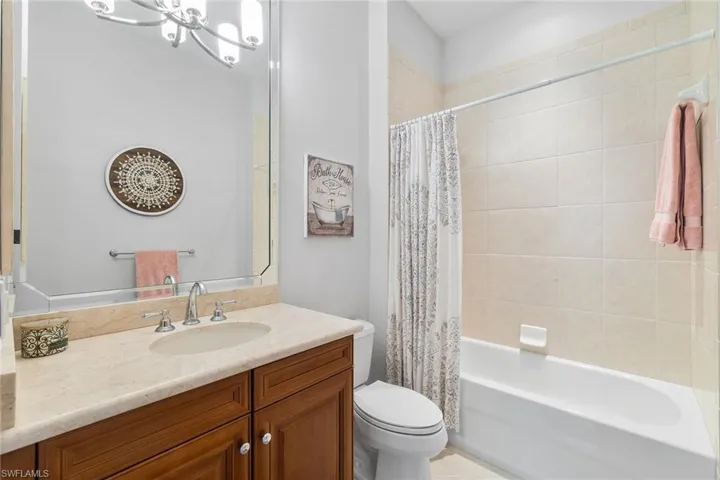 Full bath featuring vanity, shower / tub combo with curtain, and a chandelier
