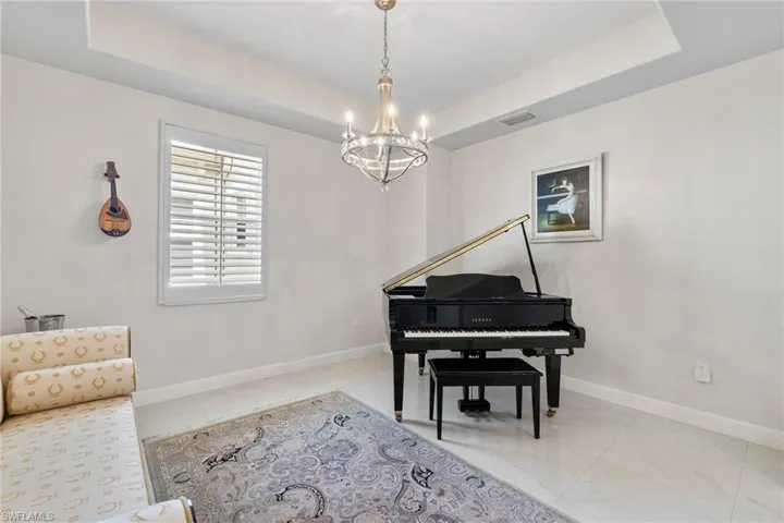 Sitting room featuring a raised ceiling, a chandelier, and light tile patterned floors