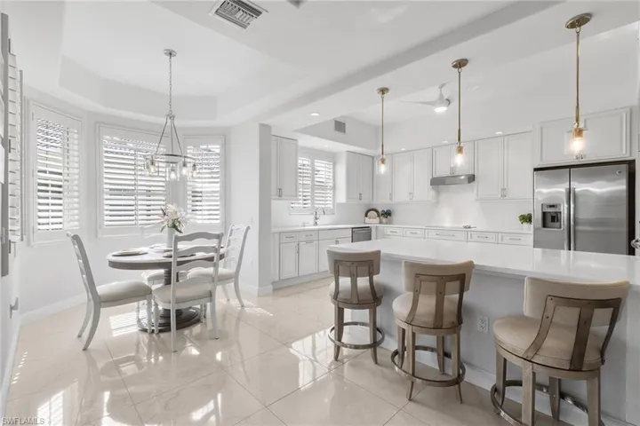Kitchen with a breakfast bar area, decorative light fixtures, appliances with stainless steel finishes, and a raised ceiling
