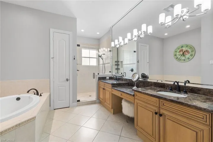 Full bathroom with double vanity, a garden tub, light tile patterned floors, and a stall shower