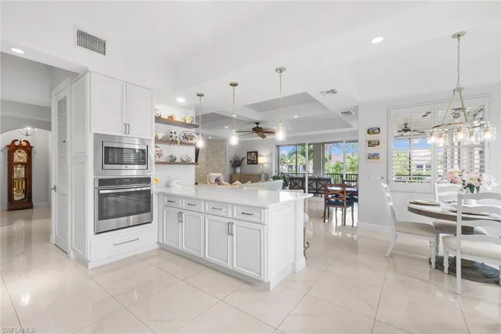 Kitchen with stainless steel appliances, white cabinets, a ceiling fan, open shelves, and hanging light fixtures