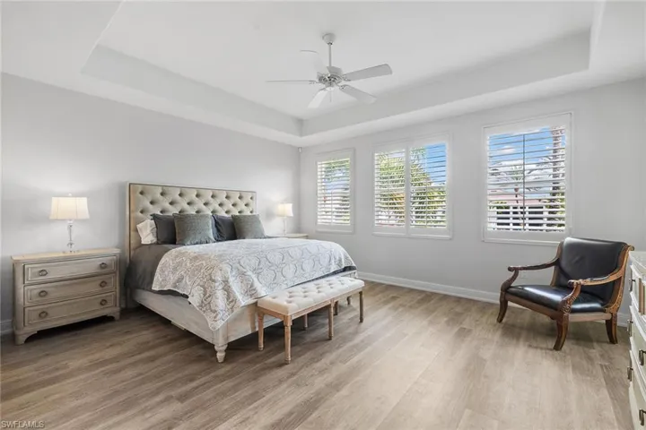 Bedroom with a raised ceiling, light wood-style floors, and ceiling fan