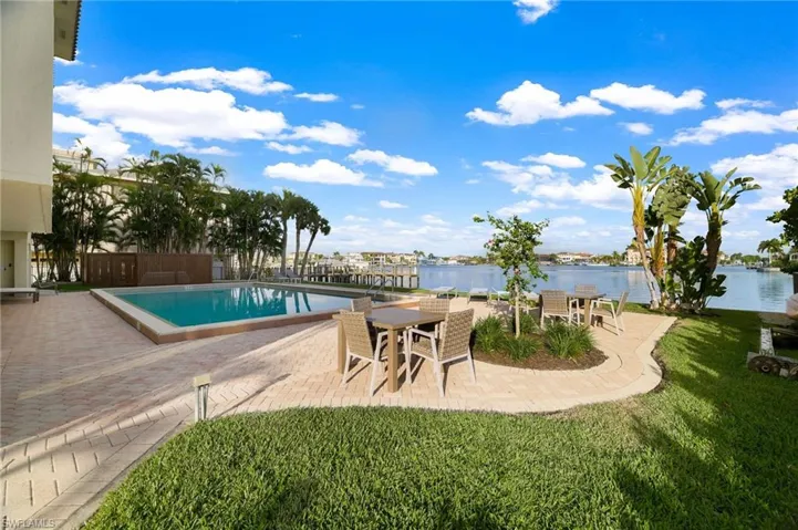 Community pool with a patio area, a water view, and a lawn