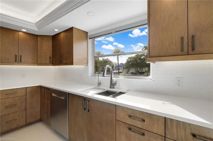 Kitchen featuring decorative backsplash, stainless steel dishwasher, brown cabinets, recessed lighting, and crown molding