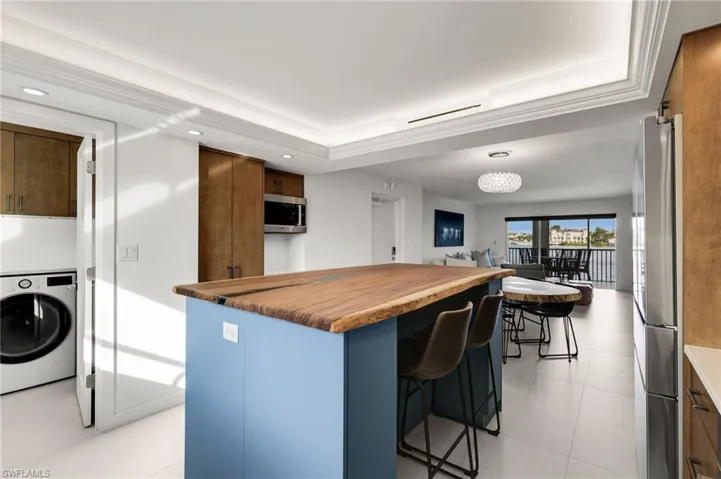 Kitchen with washer / dryer, hanging light fixtures, a breakfast bar, a center island, and stainless steel appliances