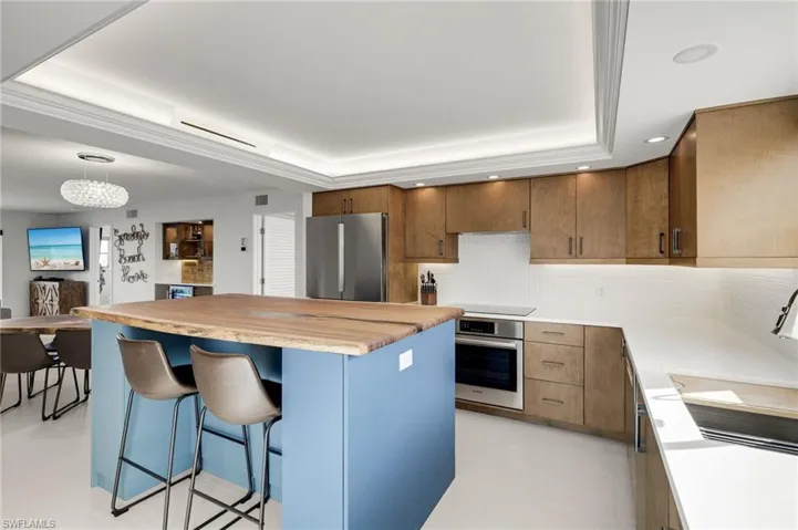 Kitchen featuring a center island, a kitchen breakfast bar, stainless steel appliances, decorative backsplash, and a tray ceiling