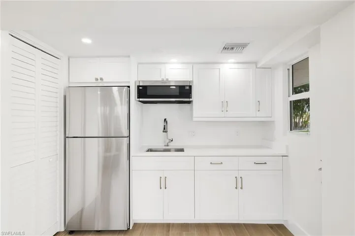 Kitchen with appliances with stainless steel finishes, white cabinetry, light countertops, recessed lighting, and light wood-style floors