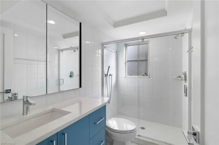 Bathroom with vanity, a stall shower, recessed lighting, and tile walls