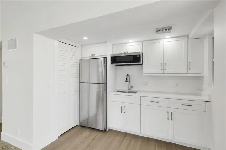 Kitchen featuring stainless steel appliances, white cabinetry, light wood-type flooring, and recessed lighting
