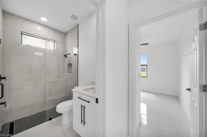 Full bath featuring light marble finish floors, a marble finish shower, vanity, and recessed lighting