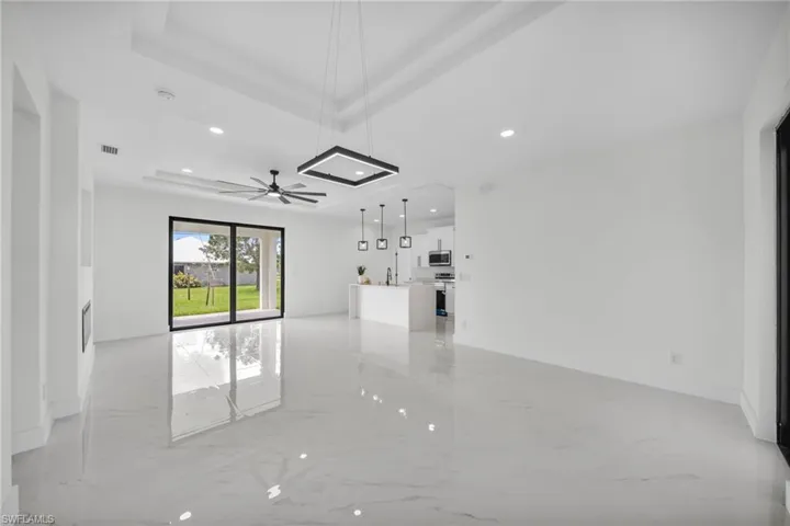 Unfurnished room with light marble finish flooring, recessed lighting, a tray ceiling, and ceiling fan