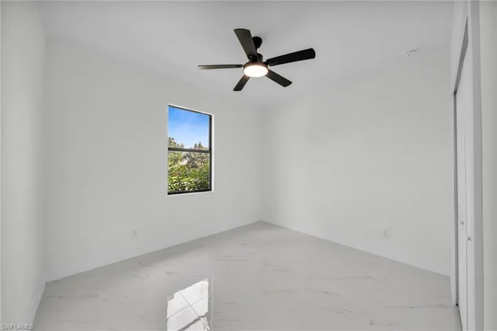 Spare room featuring light marble finish flooring and a ceiling fan